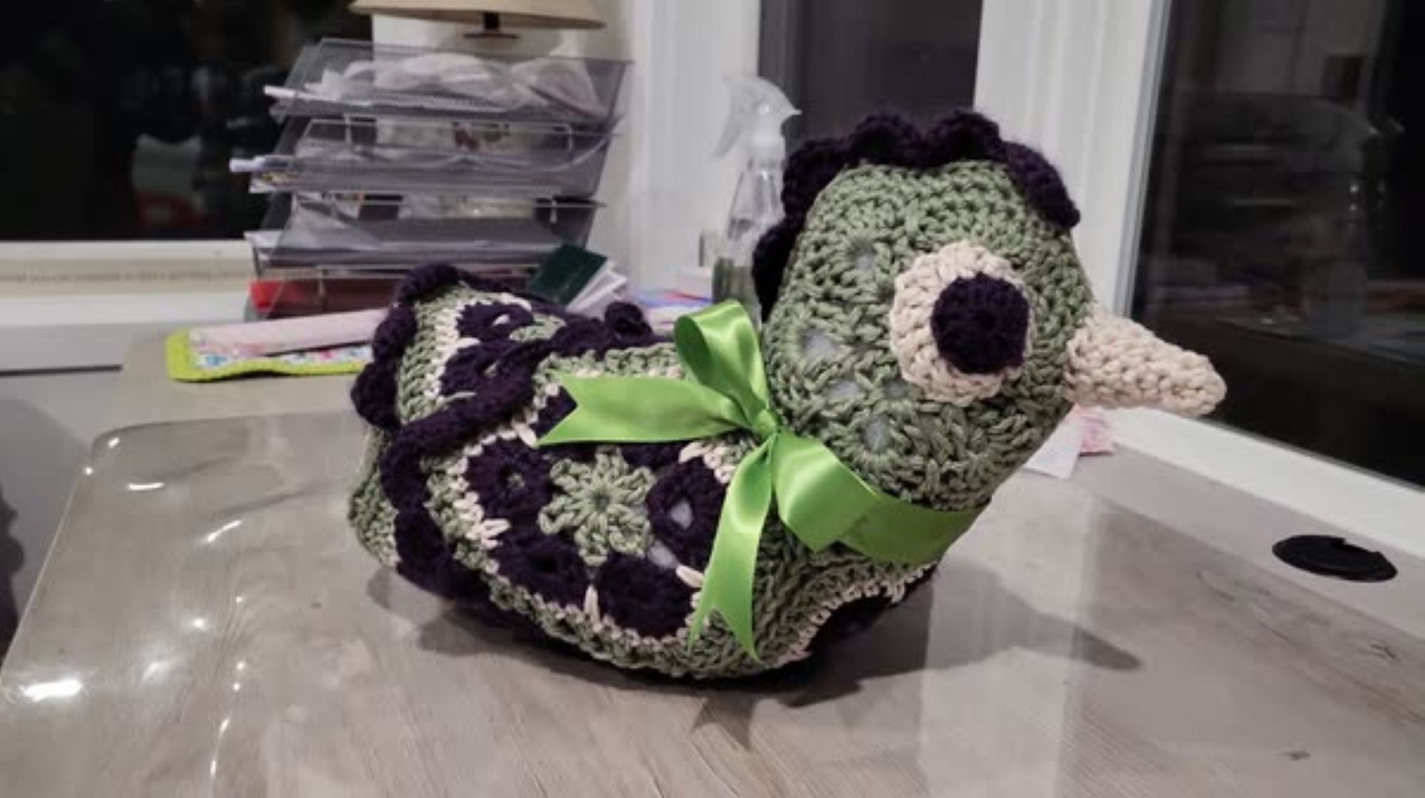 A crochet purple green and white chicken made with African flower crochet
