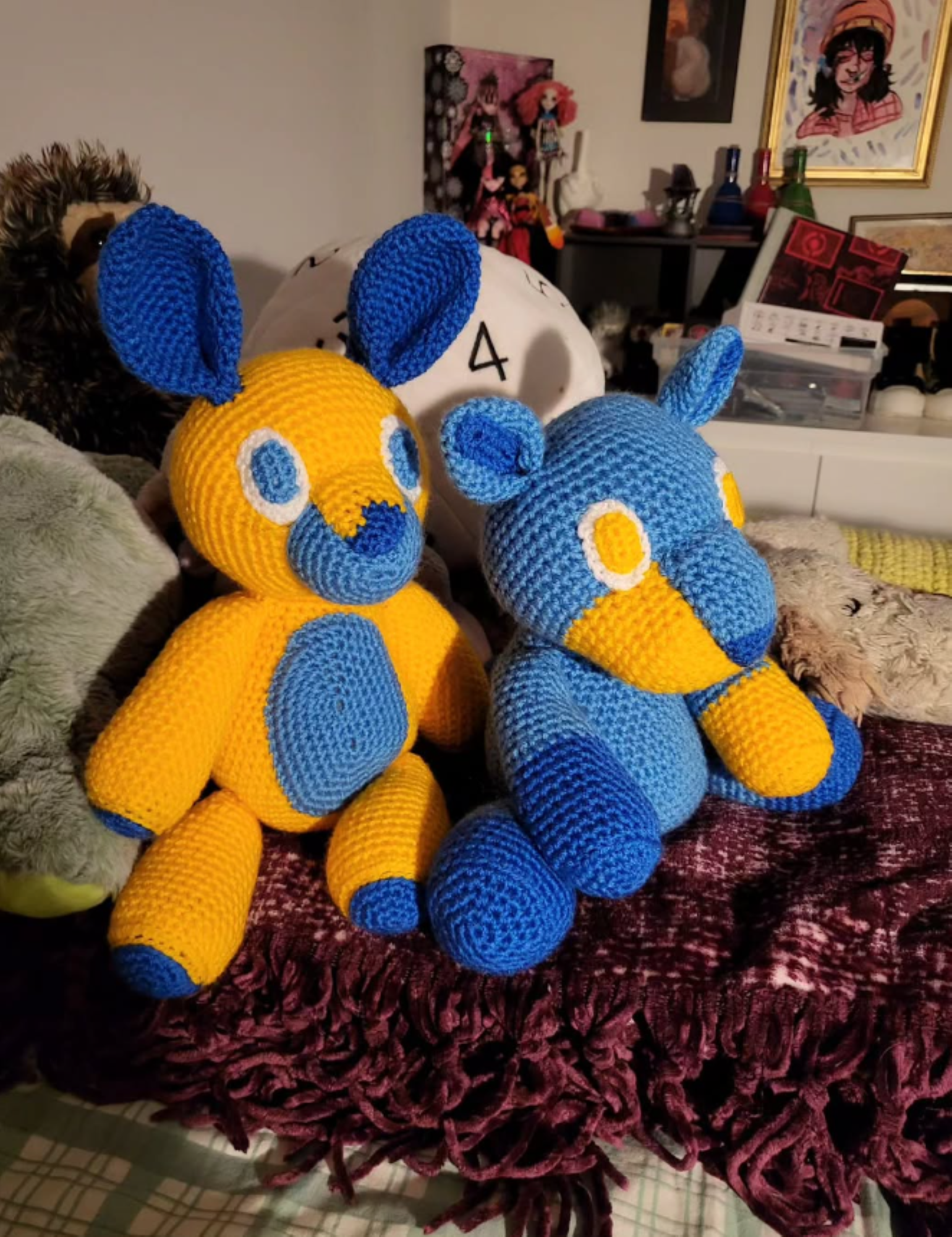 Two crochet plushies, one a bunny one a wolf, both are yellow blue and dark blue